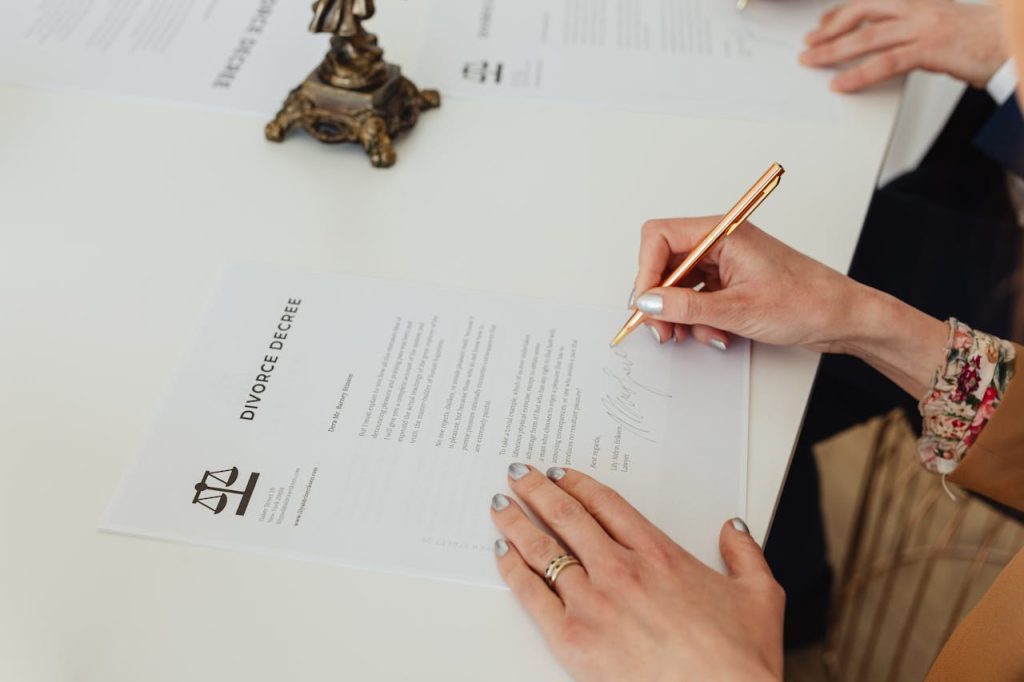 person-signing-on-white-paper-7876053 Close-up of hands signing a divorce decree document on a desk, showcasing legal process.